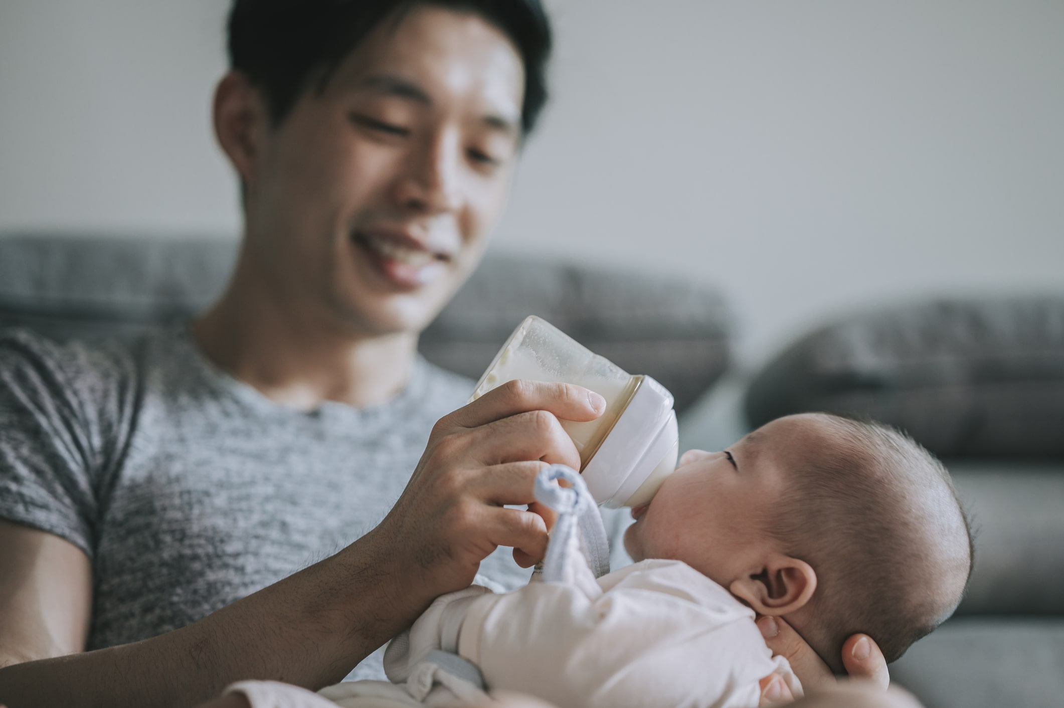 Happy dad feeding newborn baby.